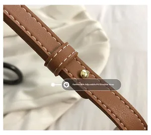Detail of adjustable brown PU leather shoulder strap with white stitching and gold buckle