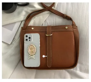 Close-up of brown leather bag showing lychee grain texture and metal buckle detail