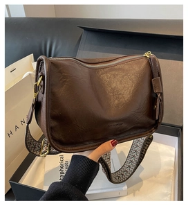 Dettaglio borsa a tracolla marrone vintage con ampia tracolla geometrica e fibbie dorate
