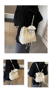 Detail of white bucket backpack with embossed patterns, drawstring, and cloud charm
