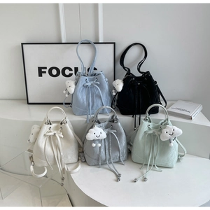 Detail of colorful drawstring bucket backpacks with cute white cloud plush charms and metal hardware