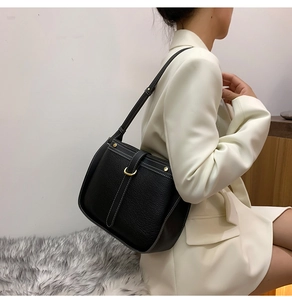 Close-up of black lychee leather bag with white stitching and gold hardware detail