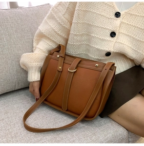 Detail of vintage brown litchi grain leather bag with contrast stitching and golden D-ring