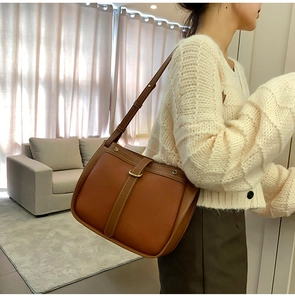 Macro detail of brown leather crossbody bag featuring vintage white contrast stitching