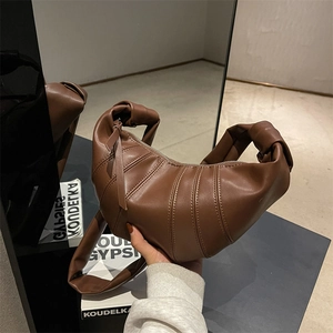 Dark brown quilted leather croissant bag with knotted handle and minimalist moon silhouette