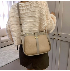 Close-up of vintage beige crossbody bag with brown leather trim and gold hardware detail