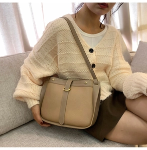 Close-up of khaki saddle bag featuring litchi texture leather and golden metal buckle