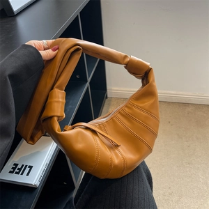 Brown croissant shoulder bag with pleated leather texture and knotted strap detail