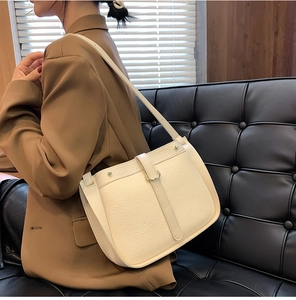 Detailed texture of creamy beige lychee grain leather bag with elegant gold metal buckle