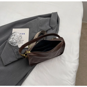 Dettaglio borsa in pelle marrone con tracolla intrecciata e doppie tasche interne