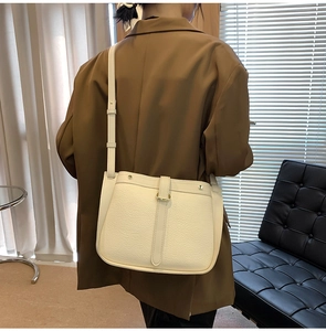 Detail view of cream pebbled leather crossbody bag with gold ring and adjustable strap