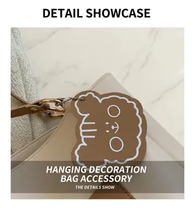 Detail of a brown bear leather charm on an off-white pebble grain tote bag