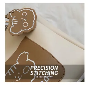Detail shot of meticulous stitching on beige tote bag with a brown bear-shaped pocket