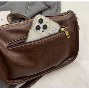Dettaglio borsa a tracolla retrò marrone scuro con tasca a zip per riporre lo smartphone