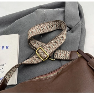 Dettaglio borsa in pelle marrone con tracolla intrecciata a motivi zigzag colorati