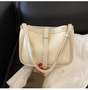 Detailed view of cream leather shoulder bag featuring lychee texture and gold ring hardware