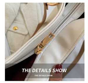 Close-up of golden metal zipper on cream white leather bag with deep red fabric lining