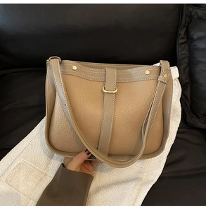 Brown lychee leather crossbody bag featuring white stitching and gold metal ring detail