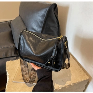 Dettaglio della borsa a tracolla cilindrica nera con cinturino floreale e finiture dorate