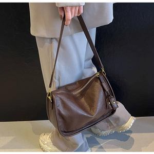 Dettaglio borsa a tracolla vintage in pelle marrone scuro con hardware dorato