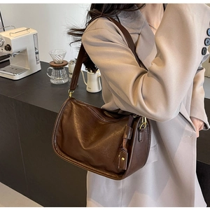 Dettaglio borsa a tracolla vintage marrone scuro con spallina larga in un caffè