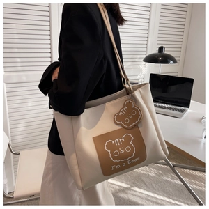 Detail showing high-capacity beige tote bag with a brown bear print and matching charm