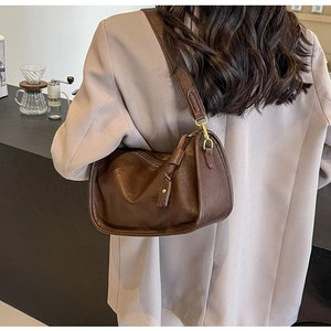 Dettaglio borsa a tracolla in pelle marrone vintage con fibbie dorate e spallina larga