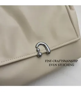 Detail of warm beige leather bag with silver U-shaped metal buckle and neat stitching