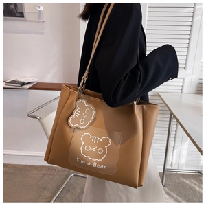 Close-up of brown PU leather tote bag with white bear print and cute bear charm detail