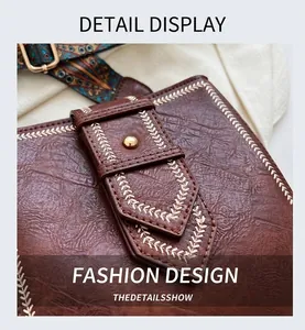 Makro-Detailaufnahme der braunen Ledertasche mit Stickerei und goldener Niete
