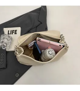 Detail showing high capacity interior of a cream shoulder bag with silver chain