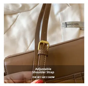 Detail view of the brown leather shoulder bag with an adjustable strap and gold buckle
