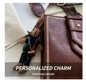 Detail der braunen Ledertasche mit V-Nähten, Ethno-Gurt und gestricktem Hasen-Anhänger