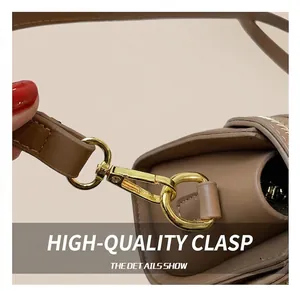 Close-up of premium gold-tone metal hook and textured brown leather strap on bag
