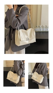 Detail of creamy white leather shoulder bag featuring bold silver chain and metal U-shaped buckle