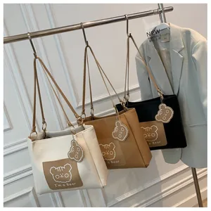 Three leather tote bags in white, brown, and black with cute bear motifs on display