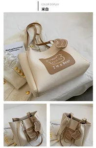 Detail view of a cream PU leather tote bag featuring a cute cartoon bear print and charm