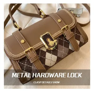 Detail of the high-gloss gold twisting lock on a vintage brown leather crossbody bag