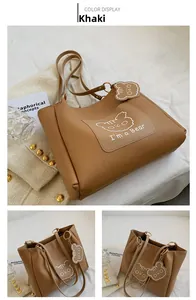 Detail of khaki tote bag with cute cartoon bear print and leather bear charm accessory