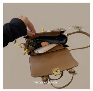 Internal capacity view of brown patterned crossbody bag holding phone and cosmetics