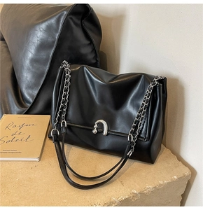 Detail of soft black leather texture and silver horseshoe metal buckle on shoulder bag