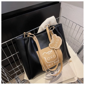 Detail of black tote bag with cartoon bear print and small bear charm in a cart