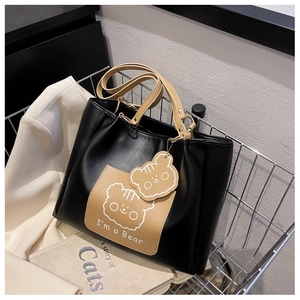 Detail of black PU leather tote bag with bear print in a metal shopping basket scene