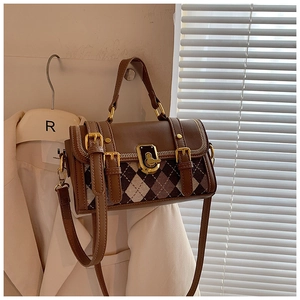 Detail of vintage brown plaid handbag featuring golden metal twist lock and leather straps
