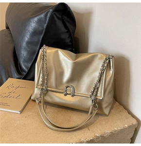 Detailed shot of golden chain strap and U-shaped metal buckle on a textured shoulder bag
