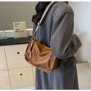 Dettaglio borsa vintage in pelle marrone con tracolla ricamata e goffratura di moda