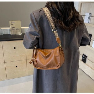 Dettaglio della borsa a bauletto marrone con tracolla jacquard larga sulla modella