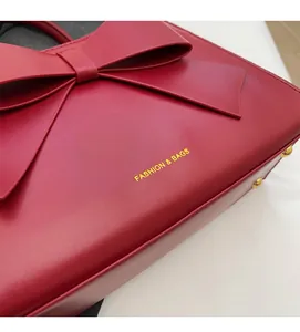 Detail of red bridal leather handbag featuring a large bow and gold fashion text
