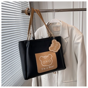 Detail of black PU tote with brown wide strap and bear print front pocket design