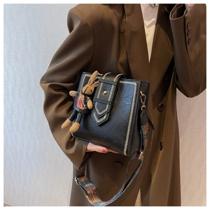 Nahaufnahme der schwarzen Retro-Tasche mit weißen V-Nähten und buntem Ethno-Schultergurt